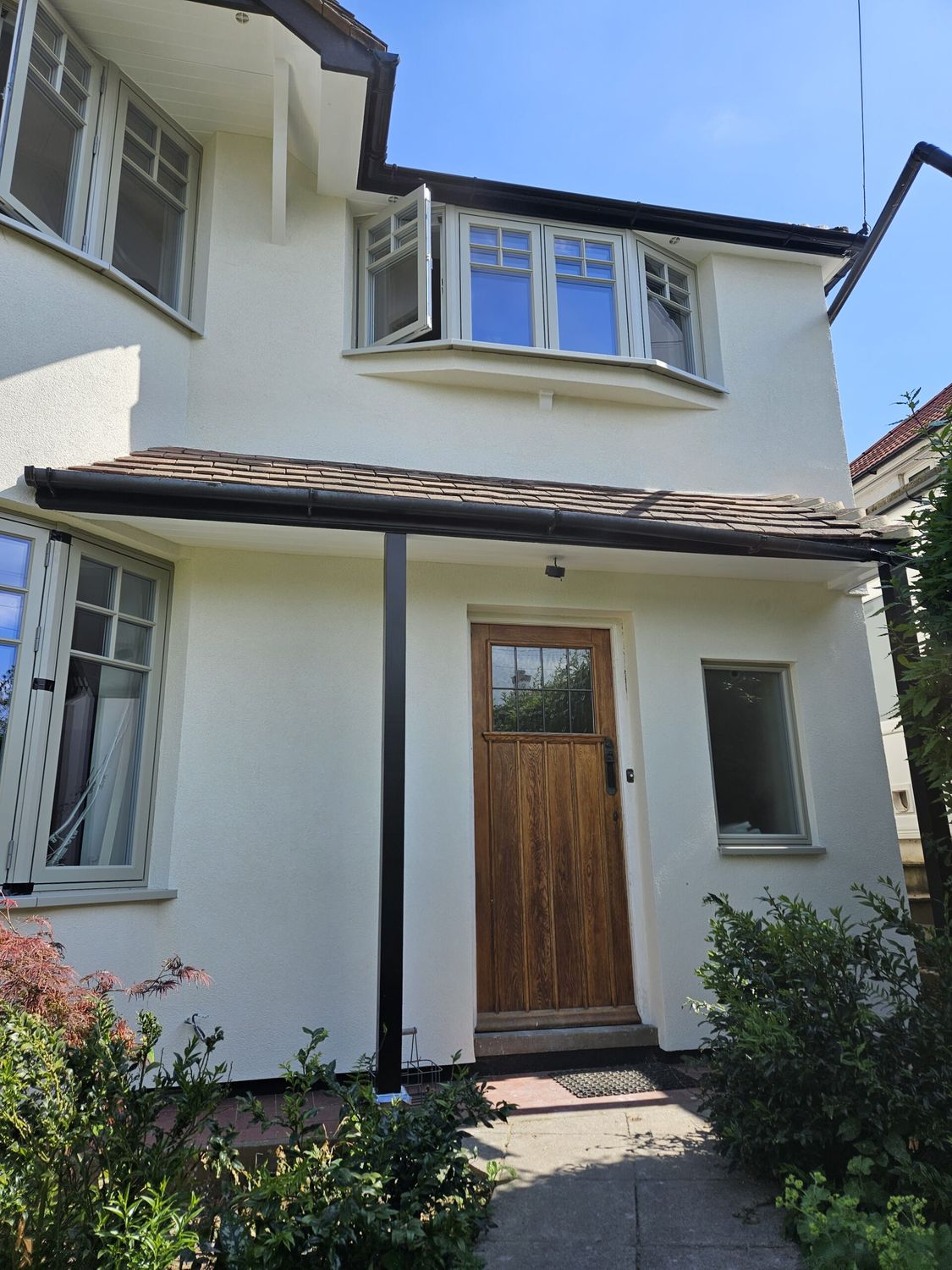 External wall insulation with wood fibre boards, silicone render finish and black mosaic plinth insulation - completed on front elevation entrance side