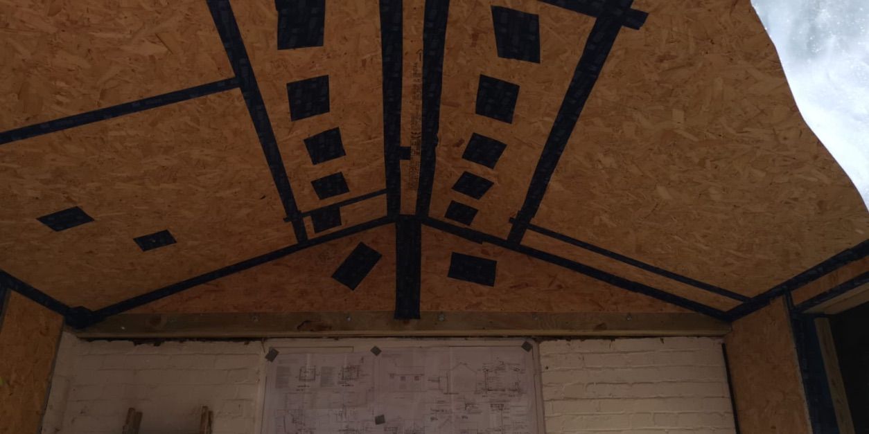 Timber frame structure filled with cellulose fibre insulation, holes taped over